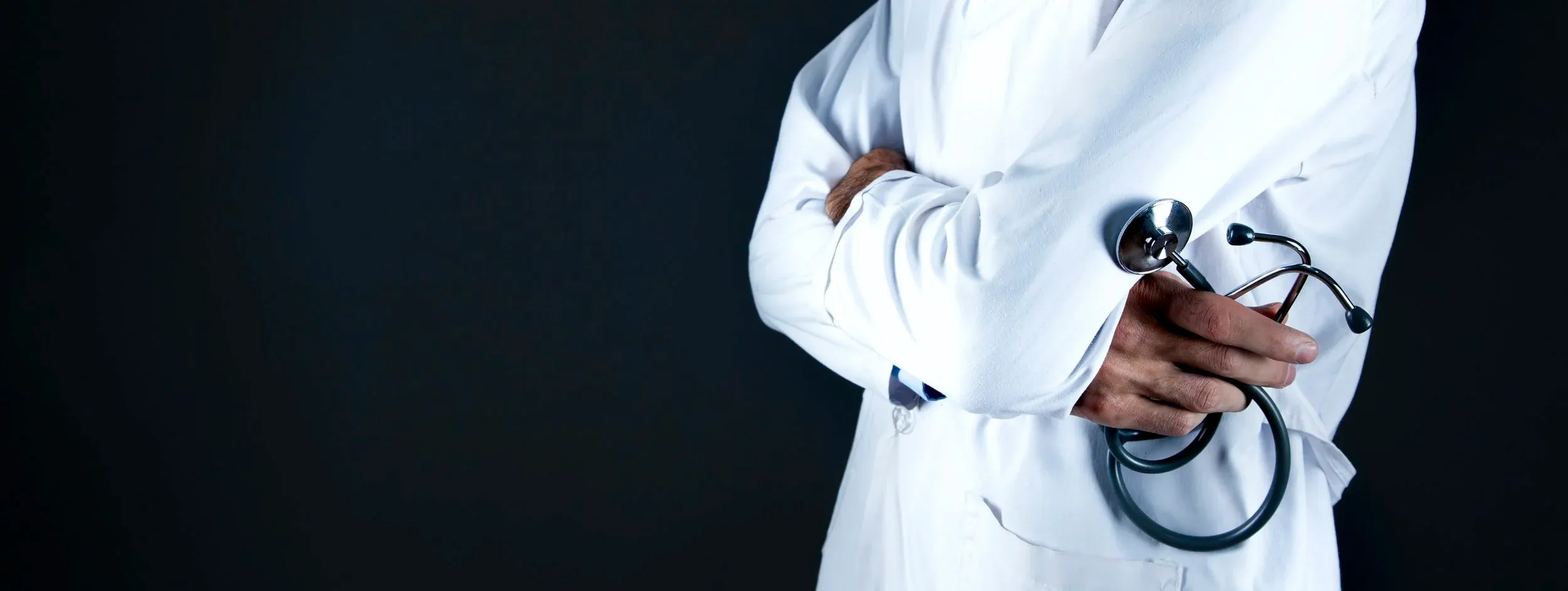 Médecin en blouse blanche, bras croisés, tenant un stéthoscope