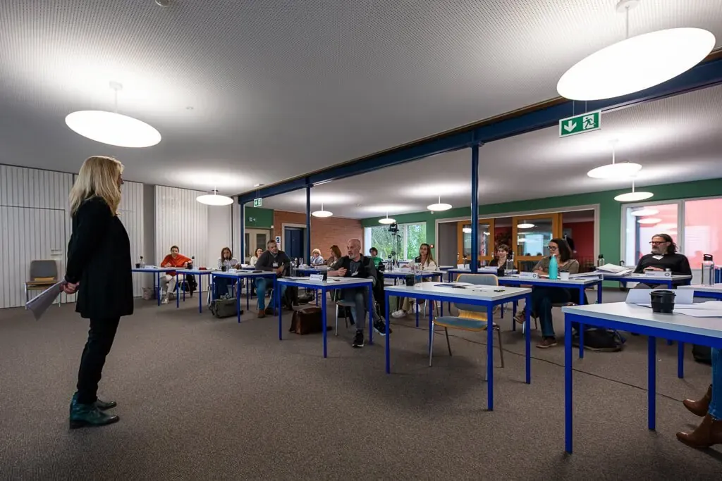Marta Hegyaljai Python s’adresse à la salle, les participant·e·s assis aux tables