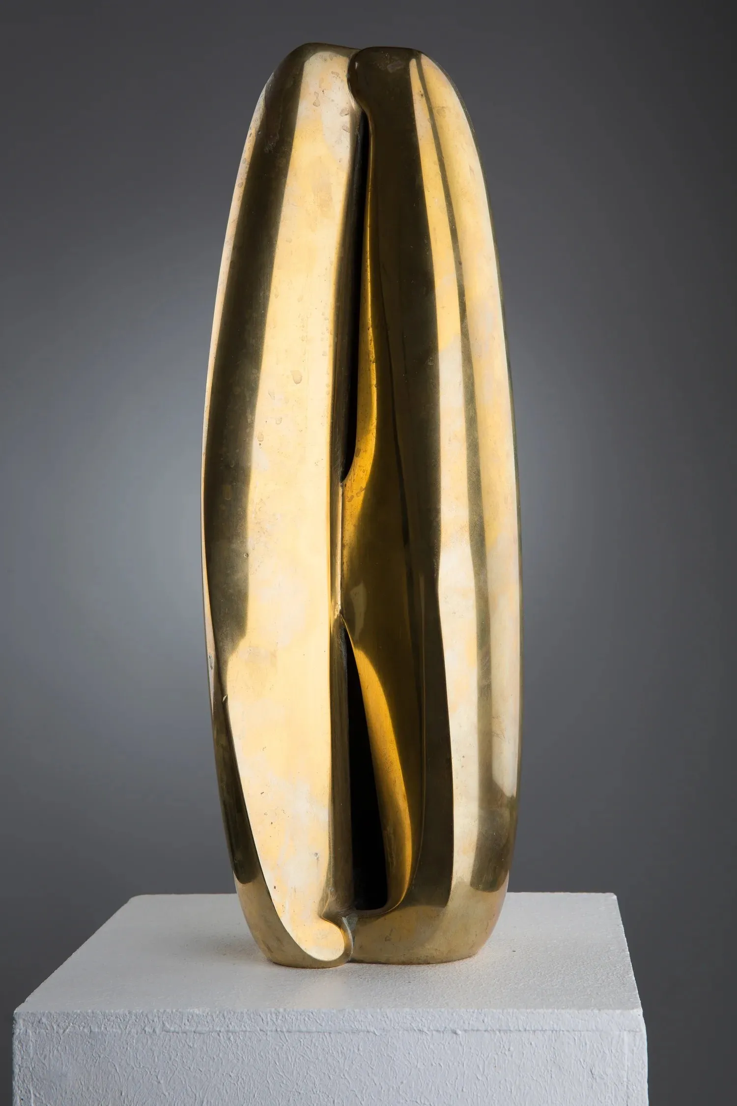 « Obelisk I » de Jan Hegy : sculpture en bronze poli, haute forme verticale fendue sur toute sa hauteur par une profonde entaille, posée sur un socle blanc.
