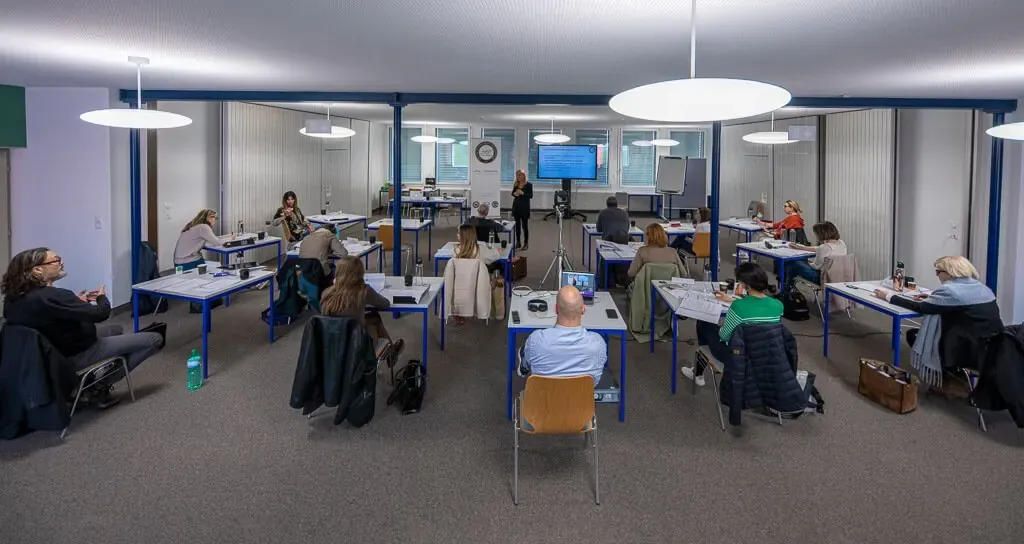 Vue d’ensemble d’une salle de formation, le groupe autour des tables